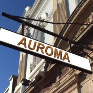 Hanging AUROMA storefront sign against facade